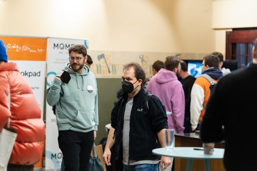 One attendee holsing a mask, another wearing his