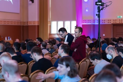 A photo of the crowd in the congress hall. Two men trying to find seats.