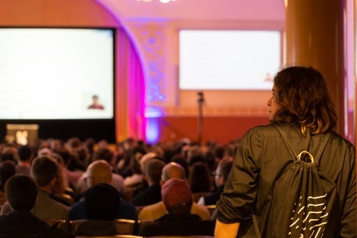 Two people peek at the keynote from the foyer