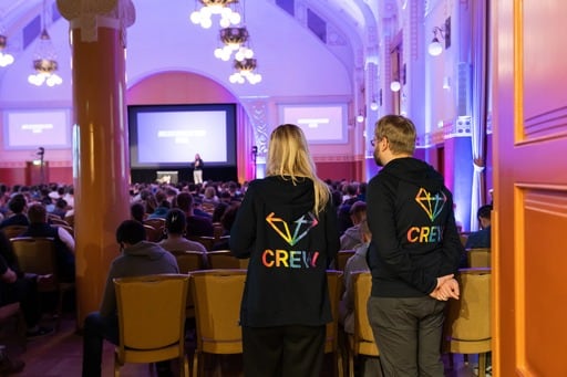 Two crew members oversee things from the back of the hall