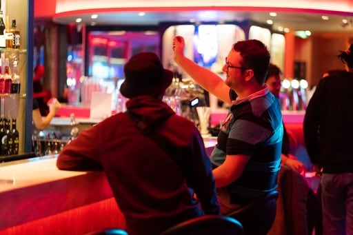 A man trying to attract the attendtion of a bartender